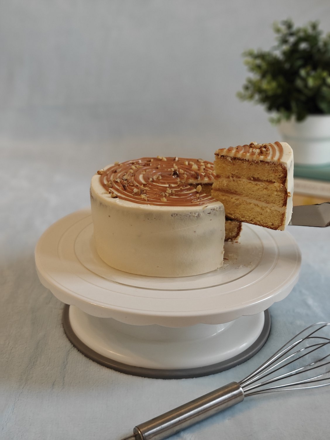 Caramel cake with cream cheese frosting, sliced to show golden sponge layers